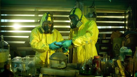 In einem Crystal-Meth-Labor. Zwei Menschen in Ganzkörperschutzkleidung packen die Droge in Tüten.
