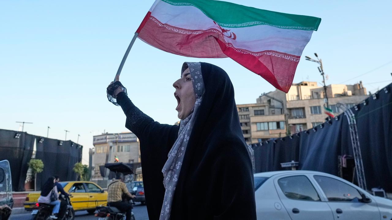 Eine Frau steht in den Straßen Teherans, hält die iranische Flagge in die Luft und ruft. Eine Frau steht in den Straßen Teherans, hält die iranische Flagge in die Luft und ruft.