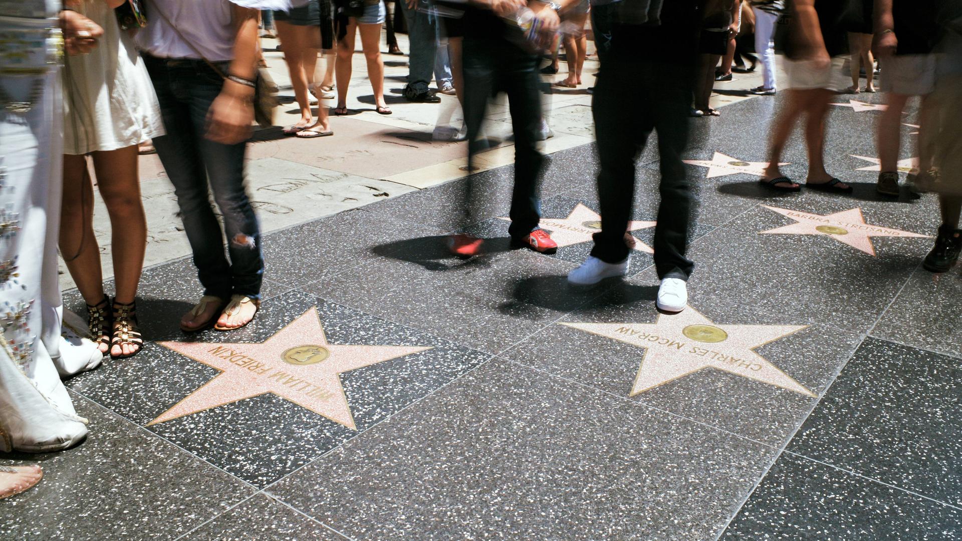 Blick auf den Hollywood Walk of Fame mit den Sternen für die Stars. Fußgänger laufen umher.