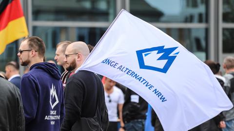 Ein Mitglied der "Jungen Alternative", der Jugendorganisation der AfD, trägt auf einer Wahlkampfveranstaltung eine Fahne mit dem Logo der Organisation.