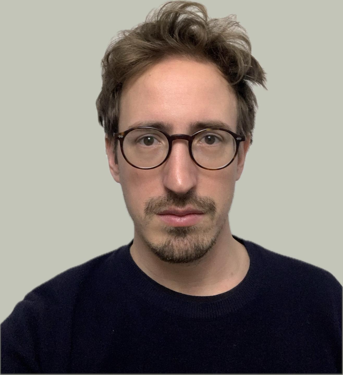 Portrait eines Mannes mit kurzen Haaren und Brille. Es ist Regisseur und Dramaturg Jakob Roth. 