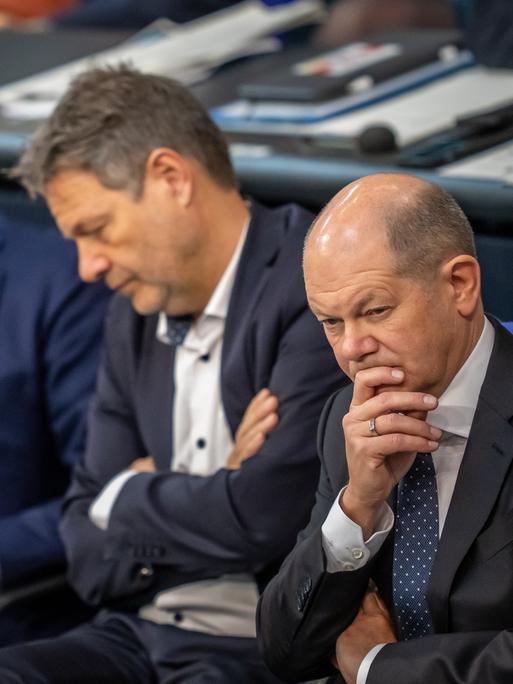 Olaf Scholz, Robert Habeck und Christian Lindner verolgen eine Rede im Bundestag.