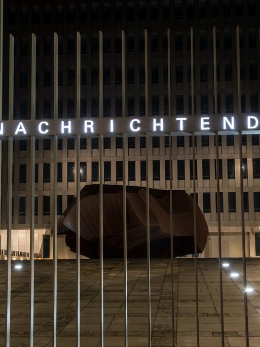 "Bundesnachrichtendienst" steht auf dem Zaun vor einem Gebäudekomplex. Hinter dem Zaun, im Hof, liegt ein Fels. "Bundesnachrichtendienst" steht auf dem Zaun vor einem Gebäudekomplex. Hinter dem Zaun, im Hof, liegt ein Fels.