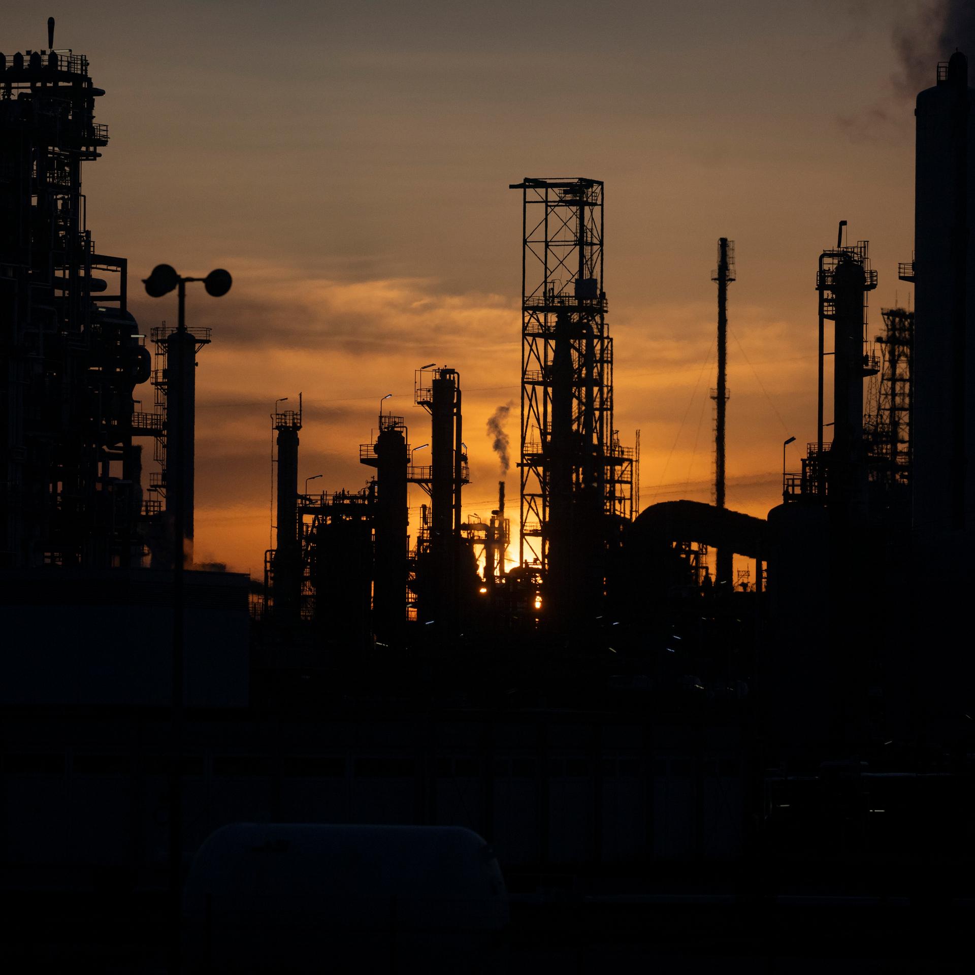 Industrieanlagen und Schornsteine der Mineralölraffinerie Oberrhein (MiRO) sind im Gegenlicht zu sehen.