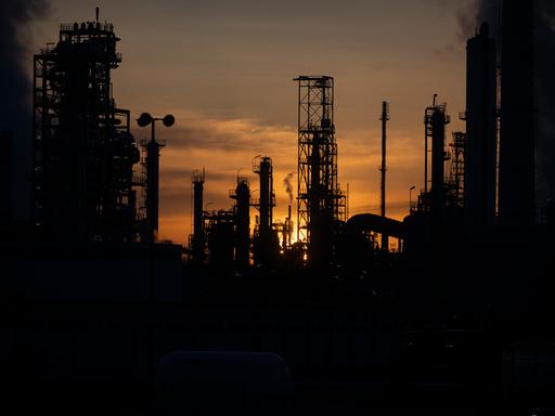 Industrieanlagen und Schornsteine der Mineralölraffinerie Oberrhein (MiRO) sind im Gegenlicht zu sehen.