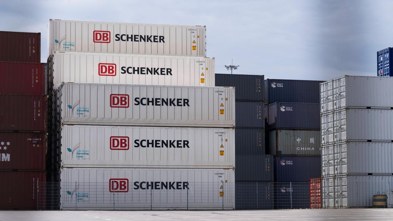 Mehrere Container mit der Aufschrift DB Schenker stapeln sich neben anderen Containern.