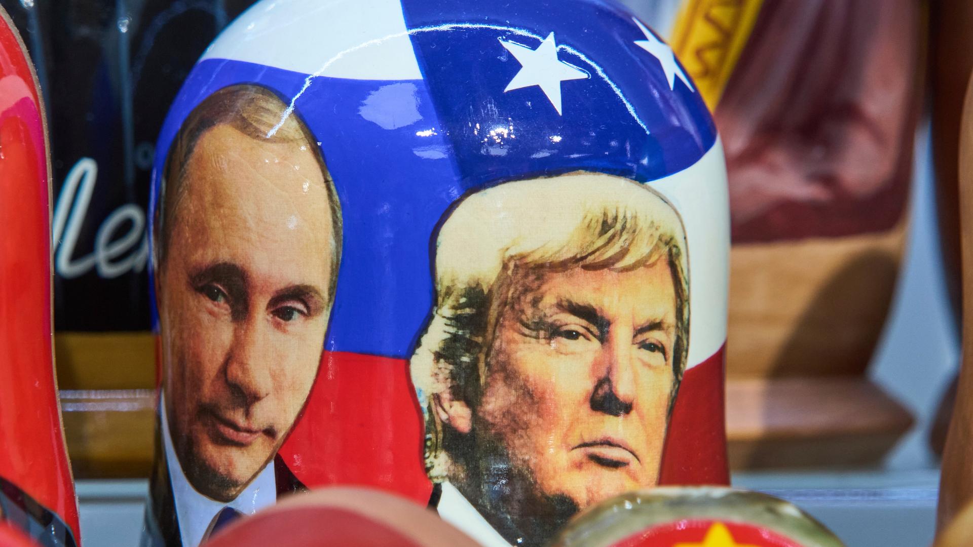 Die Gesichter von Wladimir Putin und Donald Trump, als Fotografien auf eine traditionelle russische Holzpuppe gedruckt.