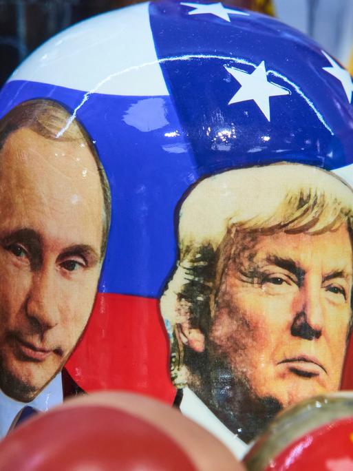 Die Gesichter von Wladimir Putin und Donald Trump, als Fotografien auf eine traditionelle russische Holzpuppe gedruckt.