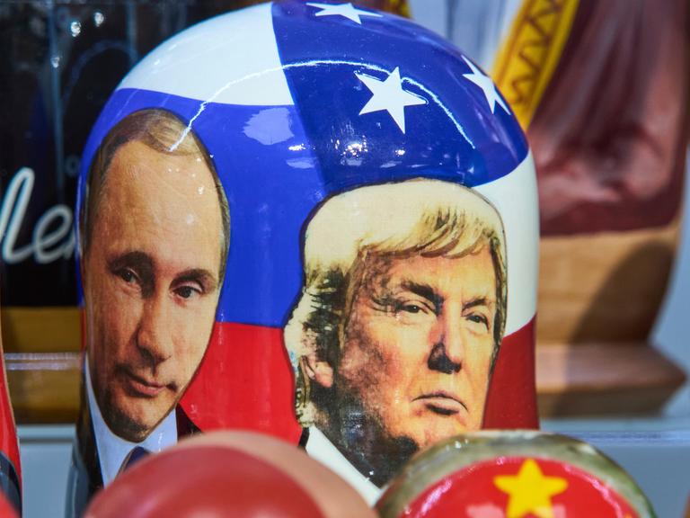 Die Gesichter von Wladimir Putin und Donald Trump, als Fotografien auf eine traditionelle russische Holzpuppe gedruckt.