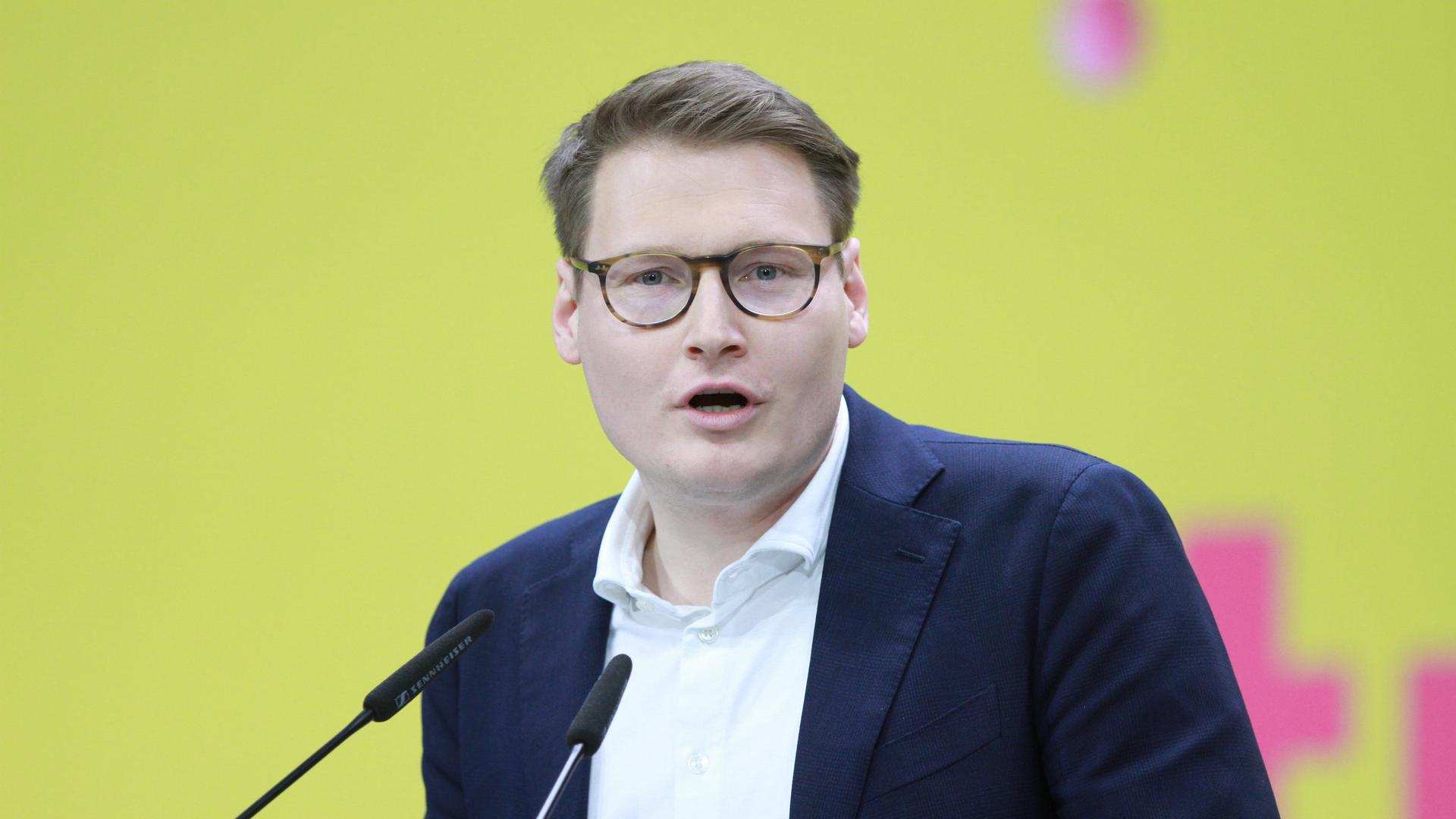 Moritz Körner hält eine Rede auf einer Bühne mit gelbem Hintergrund. Moritz Körner hält eine Rede auf einer Bühne mit gelbem Hintergrund.