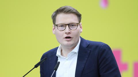 Moritz Körner hält eine Rede auf einer Bühne mit gelbem Hintergrund.