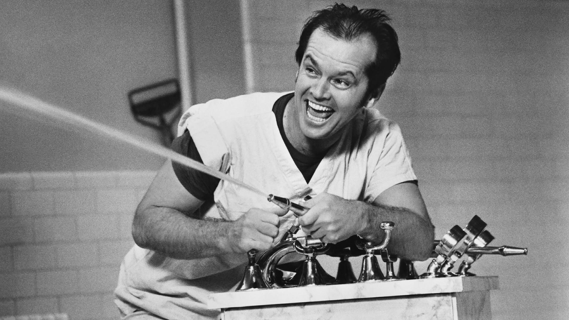 Schwarz-Weißaufnahme von Jack Nicholson, wie er mit einem Wasserschlauch spritzt und sich dabei amüsiert. Schwarz-Weißaufnahme von Jack Nicholson, wie er mit einem Wasserschlauch spritzt und sich dabei amüsiert.