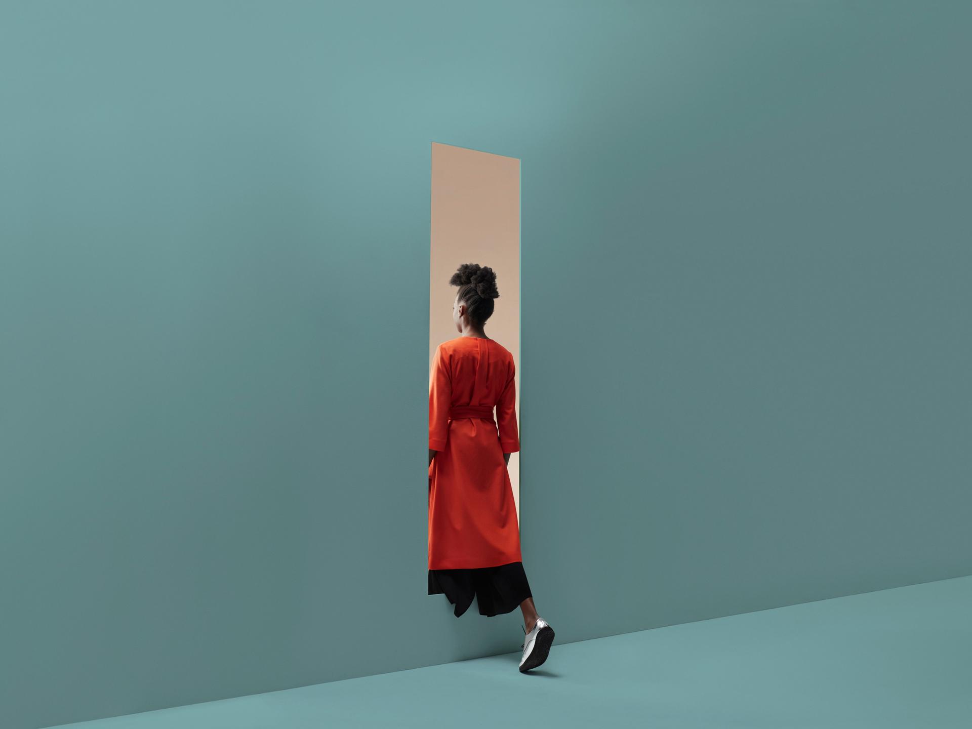 Eine Person schreitet durch die Öffnung in einer Wand.