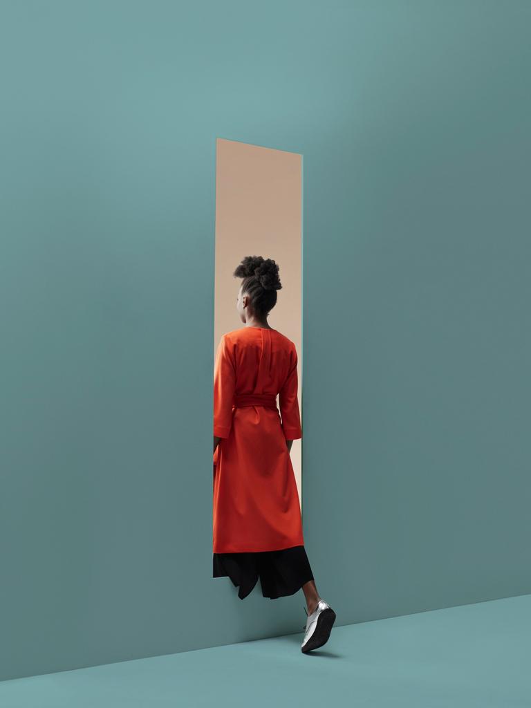 Eine Person schreitet durch die Öffnung in einer Wand.