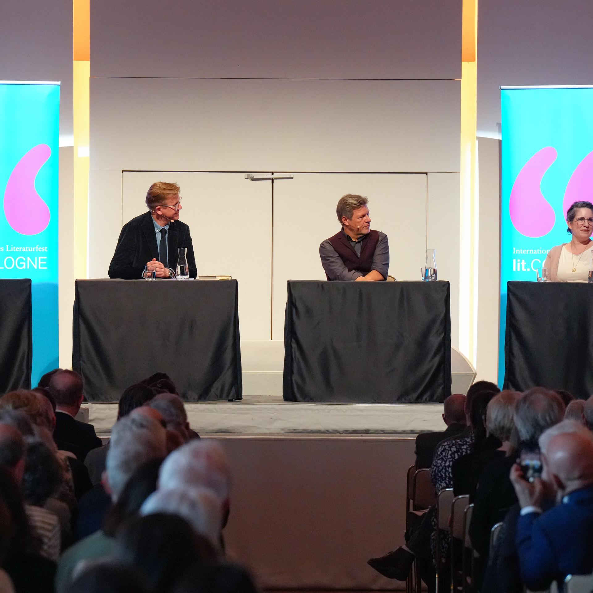 Der Schriftsteller Julian Barnes gemeinsam mit dem früheren Vizekanzler Robert Habeck bei der ersten Lesung und Eröffnung des Literaturfestivals Lit.Cologne in der Kölner Flora. Sie sitzen auf einer Bühne und sprechen miteinander. 