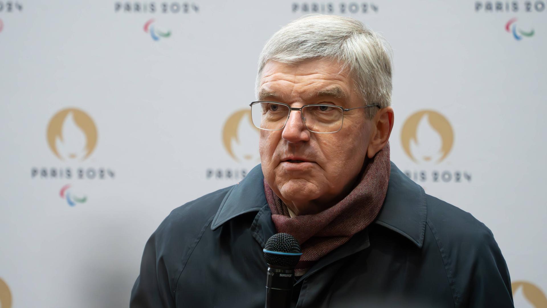 IOC-Präsident Thomas Bach mit einem Mikrofon in der Hand.