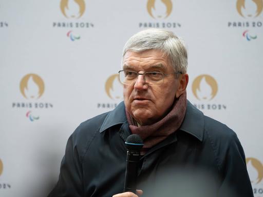 IOC-Präsident Thomas Bach mit einem Mikrofon in der Hand.