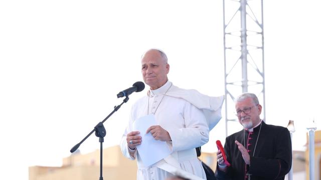 Papst Leo spricht unter freiem Himmel in ein Mikrofon.