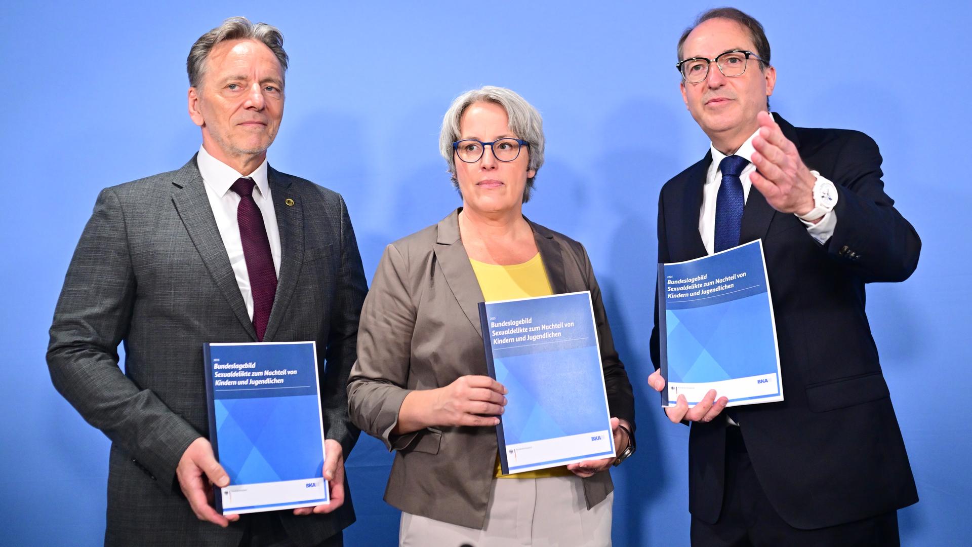 Holger Münch (l-r), Präsident des (BKA), Kerstin Claus, Unabhängige Bundesbeauftragte gegen sexuellen Missbrauch , und Alexander Dobrindt (CSU), Bundesinnenminister, stehen mit dem Lagebericht in den Händen nebeneinander. Holger Münch (l-r), Präsident des (BKA), Kerstin Claus, Unabhängige Bundesbeauftragte gegen sexuellen Missbrauch , und Alexander Dobrindt (CSU), Bundesinnenminister, stehen mit dem Lagebericht in den Händen nebeneinander.