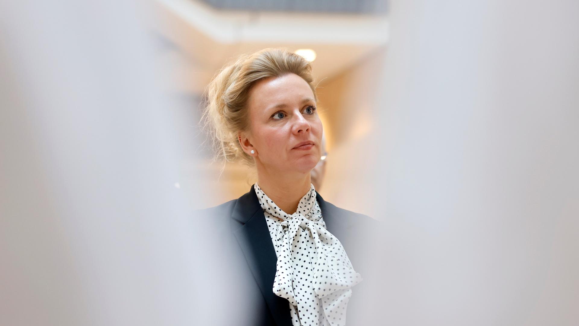 NRW-Wissenschaftsministerin Ina Brandes (CDU) hat lange, blonde Haare, die sie nach hinten zusammengesteckt hat. Zum dunklen Blazer trägt sie ein weiß-blau gepunktetes Tuch.