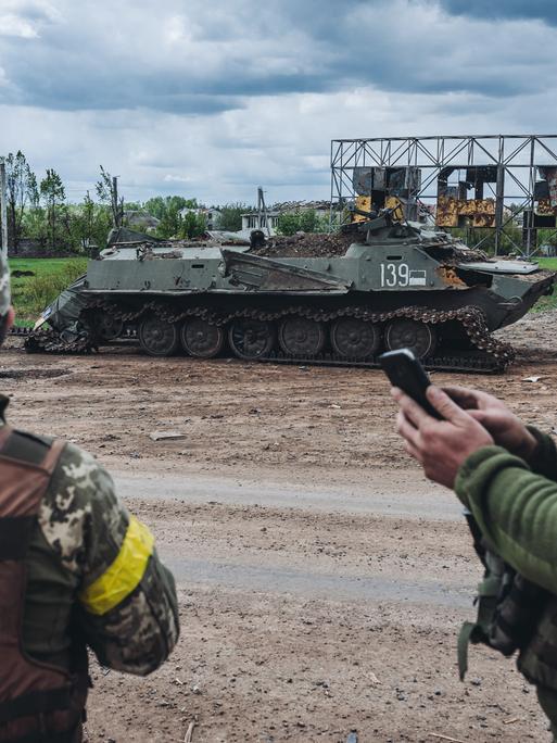 Ukrainische Soldaten vor einem zerstörten Militärfahrzeug