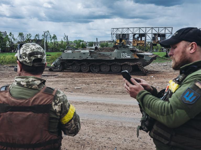 Ukrainische Soldaten vor einem zerstörten Militärfahrzeug