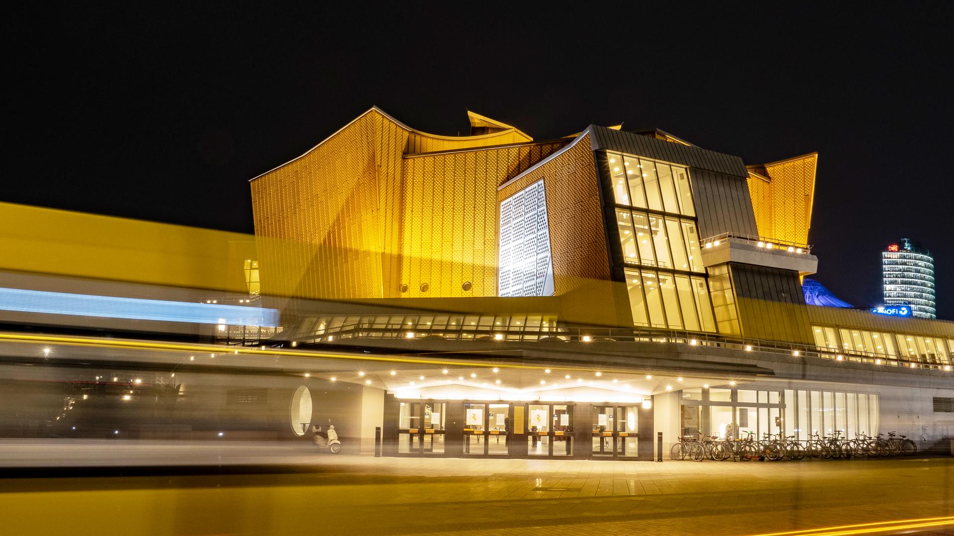 Die Berliner Philharmonie bei Nacht: Nur als Lichtstreifen zu erkennen ist, bei einer Langzeitbelichtung, ein Linienbus, der am späten Abend an der Philharmonie vorbeifährt. Sie zählt zu den wichtigsten Konzertsälen Berlins. Foto: picture alliance