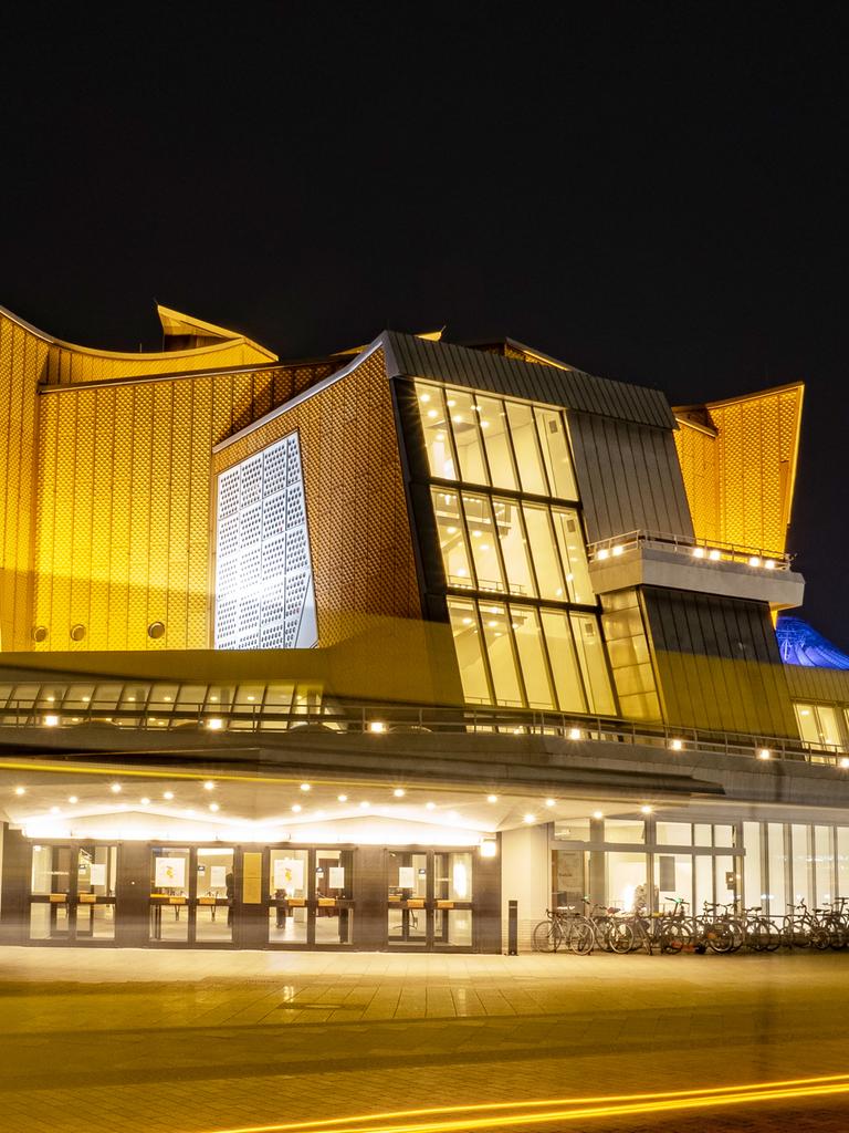 Die Berliner Philharmonie bei Nacht: Nur als Lichtstreifen zu erkennen ist, bei einer Langzeitbelichtung, ein Linienbus, der am späten Abend an der Philharmonie vorbeifährt. Sie zählt zu den wichtigsten Konzertsälen Berlins.