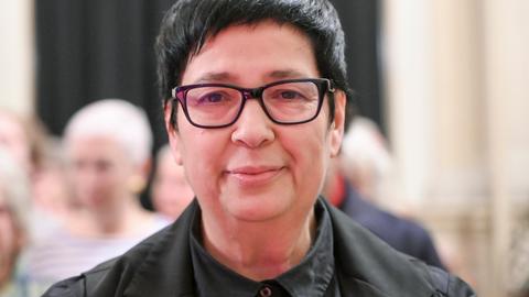 Seyran Ateş blickt lächelnd und geradeaus in die Kamera. Sie trägt eine schwarze Brille und ein schwarzes Hemd.