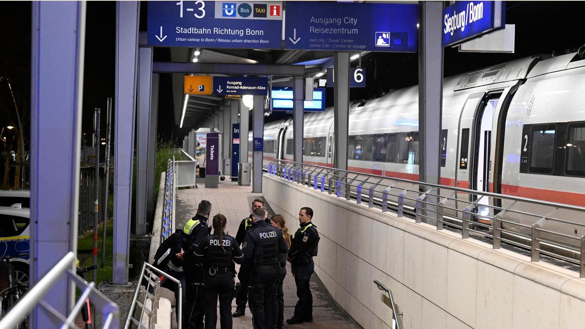 Polizisten stehen auf einem Bahnsteig im Bahnhof Siegburg/Bonn, auf dem ein ICE der Deutschen Bahn steht. 