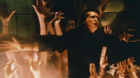 Szene aus dem Film "Der Exorzist III": Hände griefen nah einem cMann am Kreuz