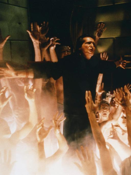 Szene aus dem Film "Der Exorzist III": Hände griefen nah einem cMann am Kreuz