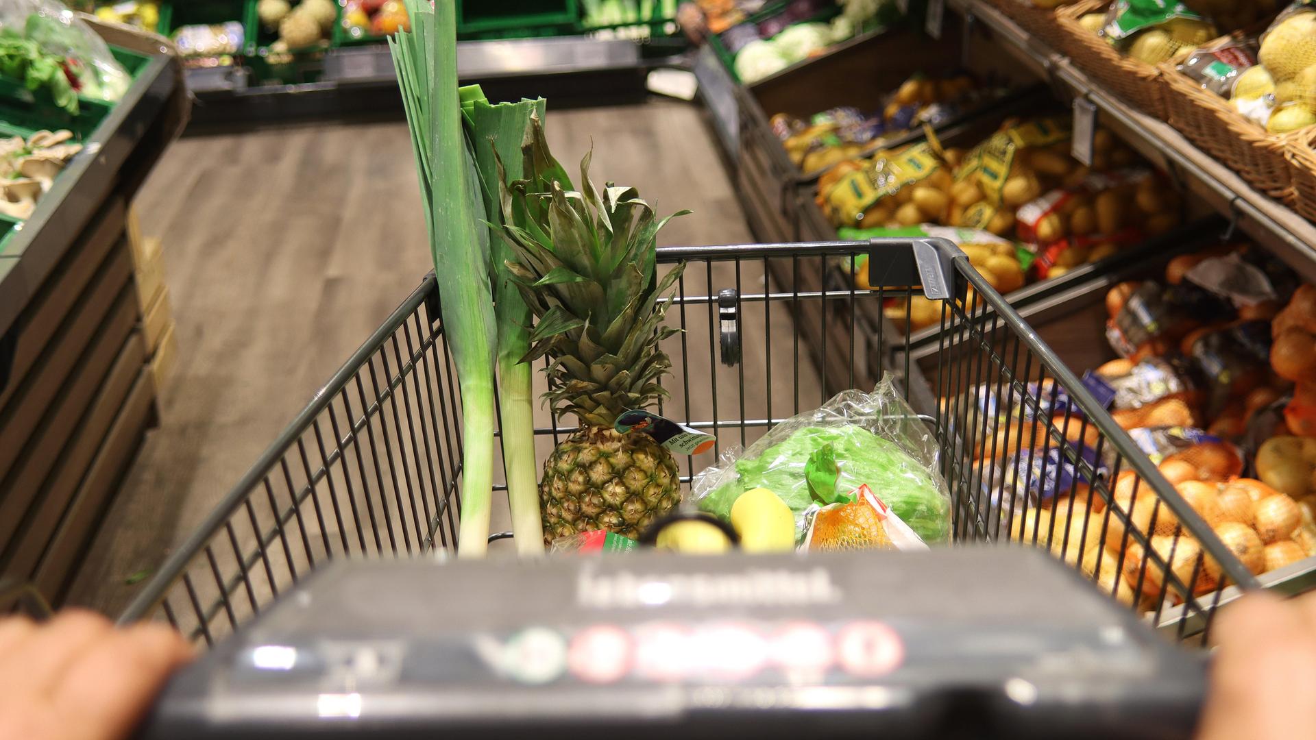 Mit Obst und Gemüse gefüllter Einkaufswagen im Supermarkt.