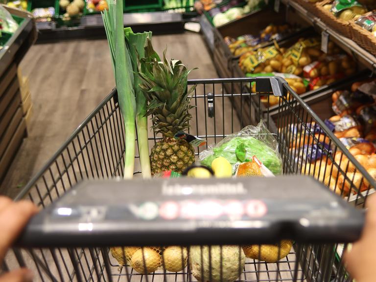 Mit Obst und Gemüse gefüllter Einkaufswagen im Supermarkt.
