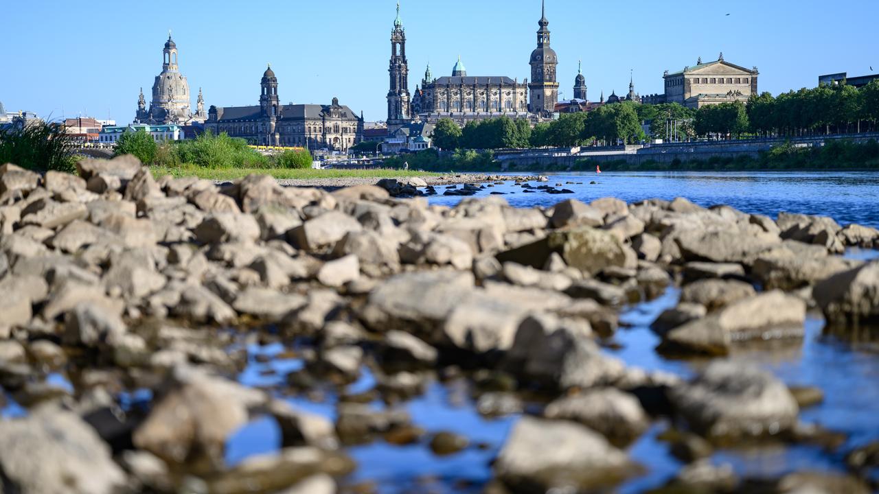 Steine liegen am ausgetrockneten Ufer der Elbe vor der historischen Altstadtkulisse von Dresden.