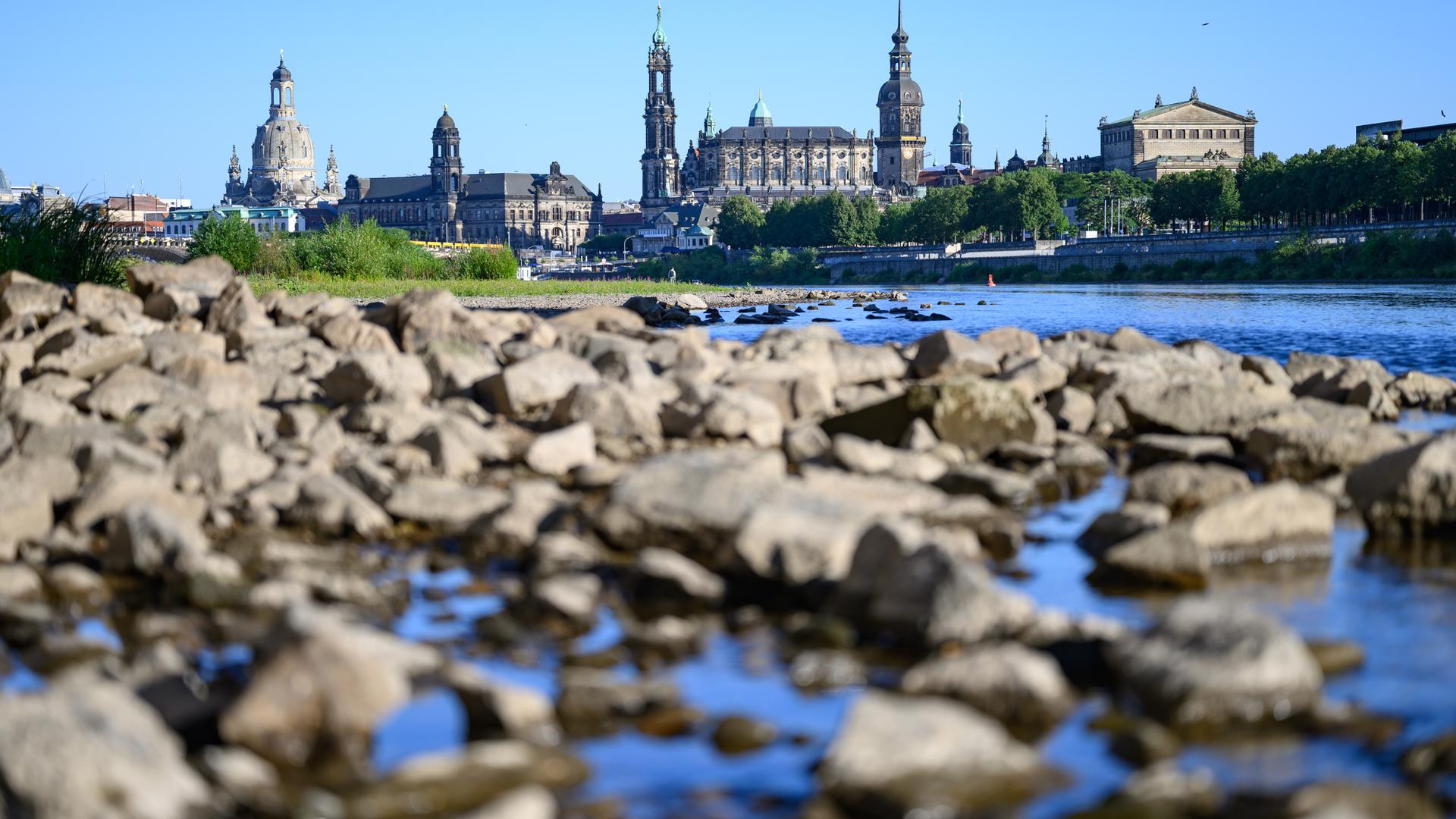 Steine liegen am ausgetrockneten Ufer der Elbe vor der historischen Altstadtkulisse von Dresden. Steine liegen am ausgetrockneten Ufer der Elbe vor der historischen Altstadtkulisse von Dresden.