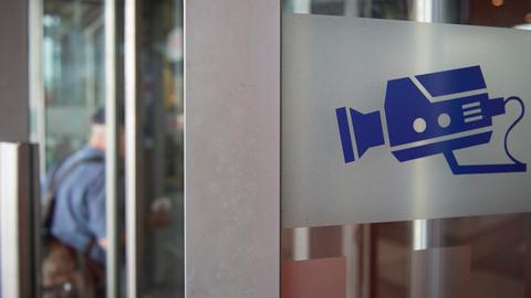Auf einem Hinweisschild ist eine Kamera abgebildet, aufgenommen an einer Eingangstür am Bahnhof