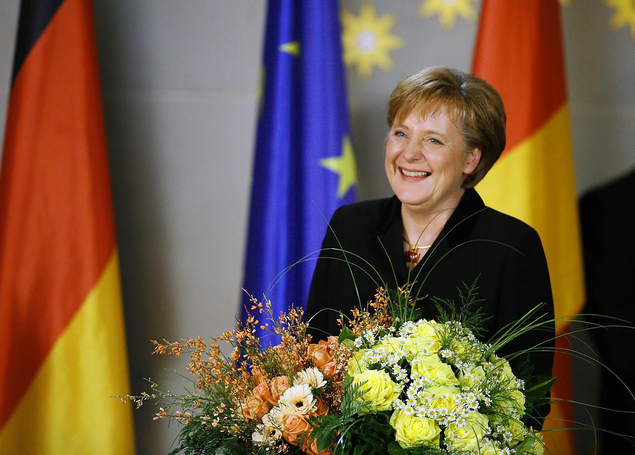 Die frischgebackene Bundeskanzlerin Angela Merkel lacht, mit Blumenstrauß in der Hand.