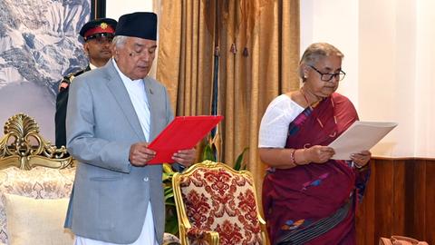 Staatschef Ram Chandra Poudel und die neue Interimsregierungschefin Sushila Karki. Sie stehen im Präsidentenpalast in Kathmandu nebeneinander und halten je ein Blatt Papier in ihren Händen. Im Hintergrund steht ein Vertreter des Militärs.