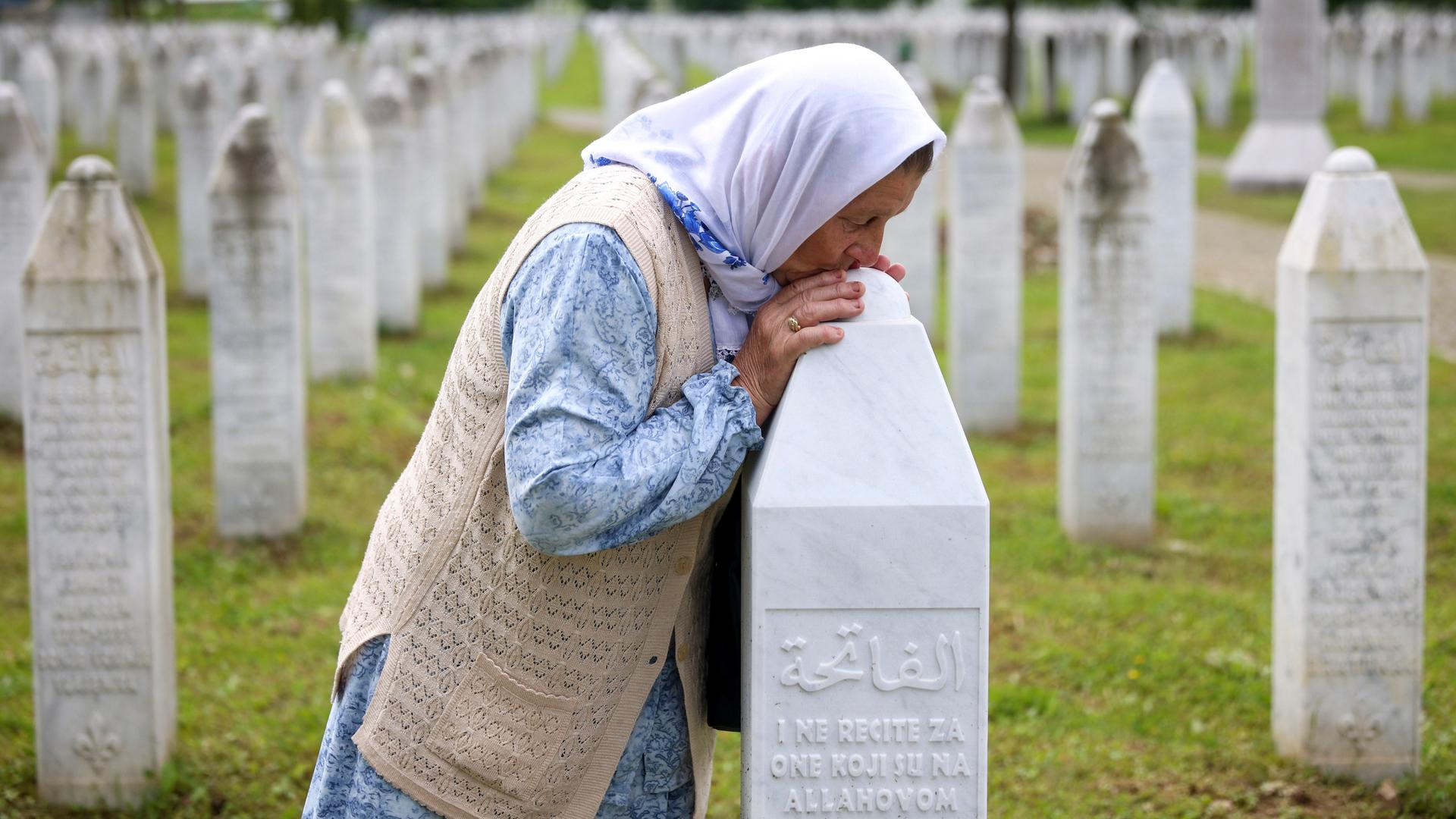 Eine bosnische Muslimim küsst das GRab ihres Sohnes in Srebrenica. 