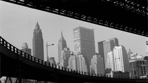 Ein schwarz weiß Foto von New York, in den USA, um 1959. Der Blick geht durch zwei Brücken auf Hochkratzer.