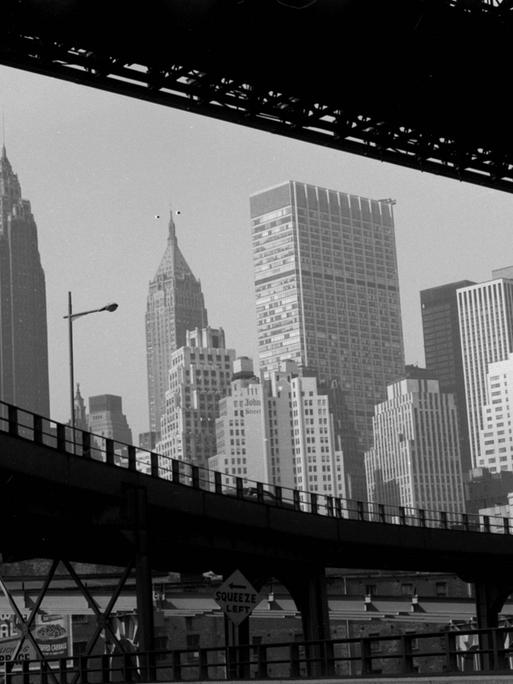 Ein schwarz weiß Foto von New York, in den USA, um 1959. Der Blick geht durch zwei Brücken auf Hochkratzer.