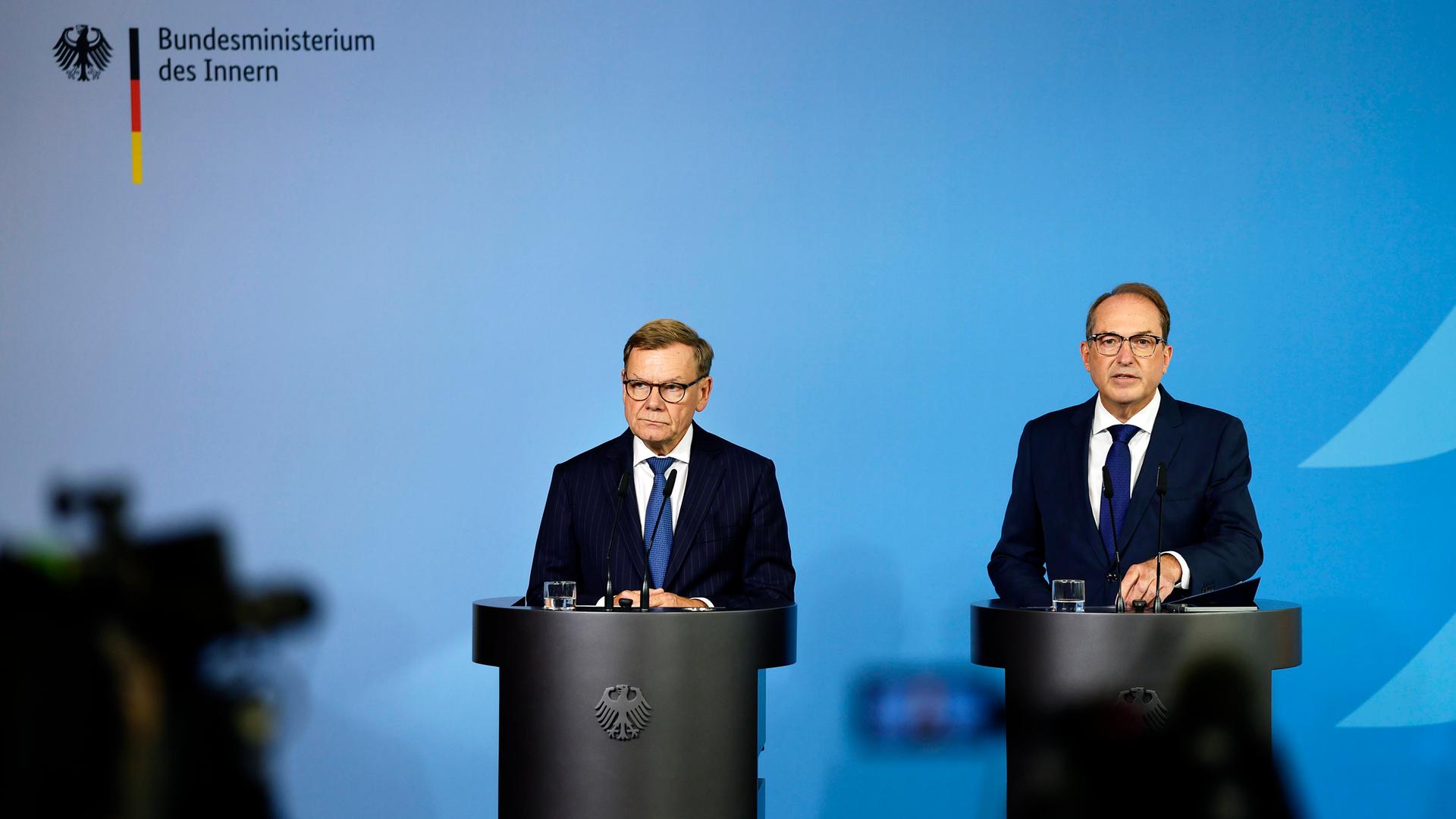 Bundesaussenminister Johann Wadephul (l., CDU) und Bundesminister Alexander Dobrindt (CSU) stehen hinter zwei Rednerpulten vor einem blauen Hintergrund, links ist der Schatten einer Kamera zu erkennen