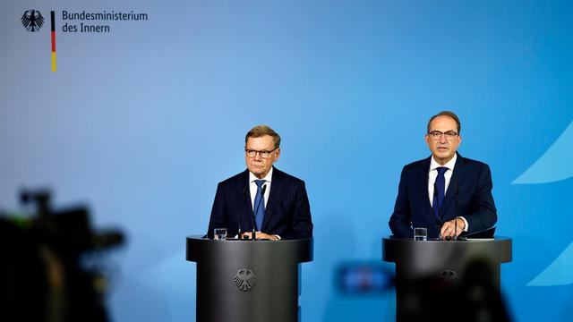 Bundesaussenminister Johann Wadephul (l., CDU) und Bundesminister Alexander Dobrindt (CSU) stehen hinter zwei Rednerpulten vor einem blauen Hintergrund, links ist der Schatten einer Kamera zu erkennen