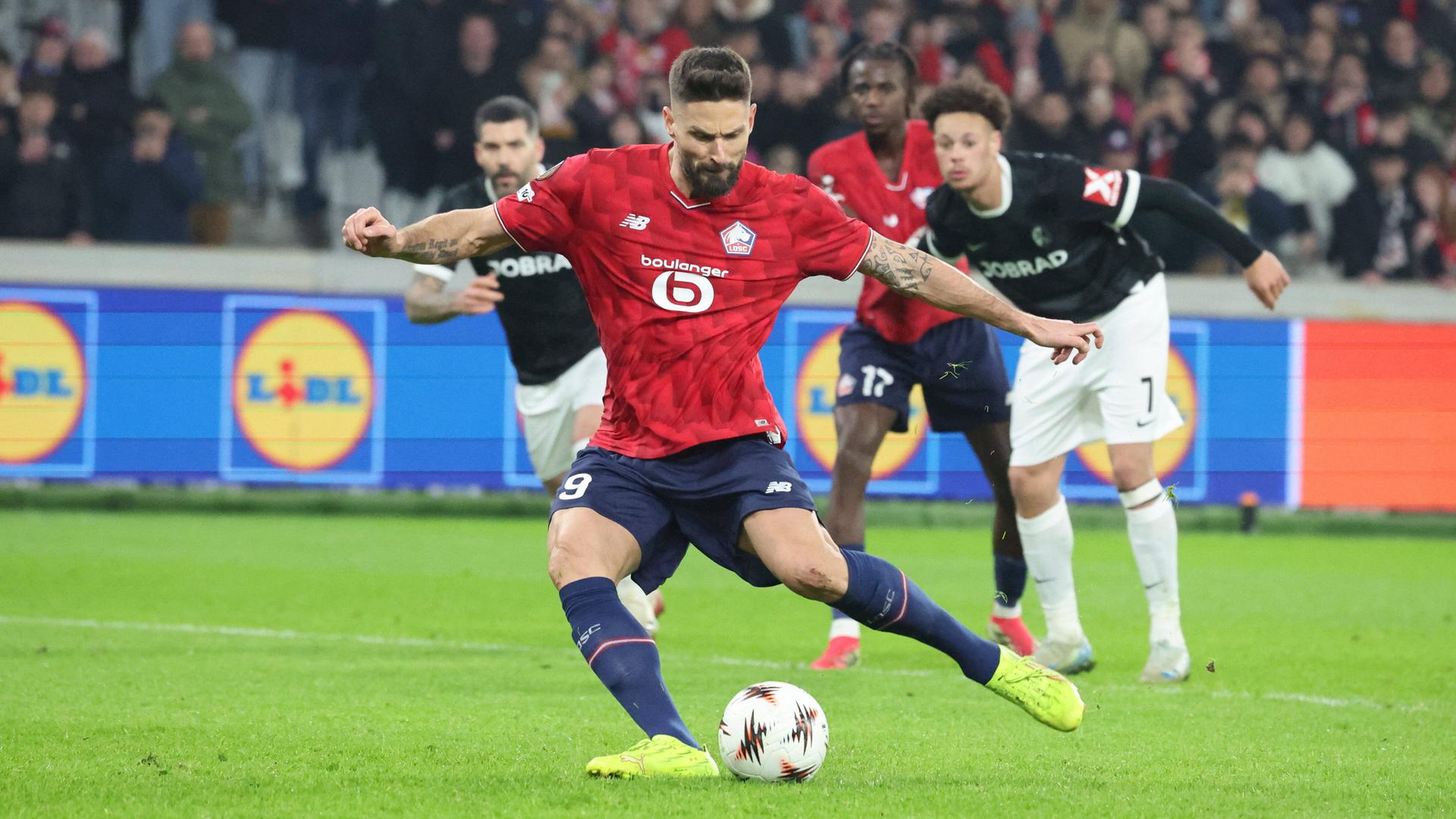 Ein Fußballspieler mit rotem Trikot zielt auf den Ball.