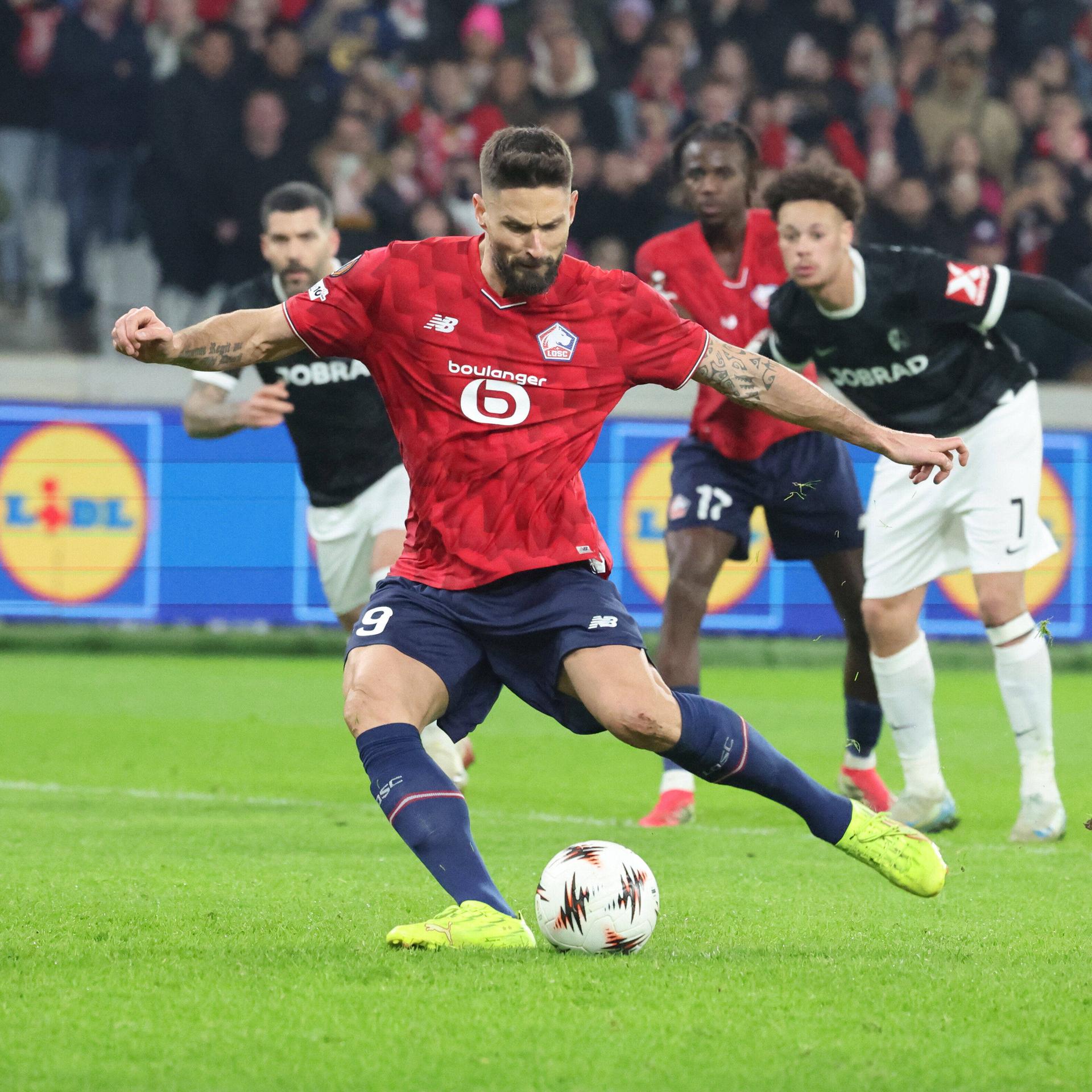 Ein Fußballspieler mit rotem Trikot zielt auf den Ball.