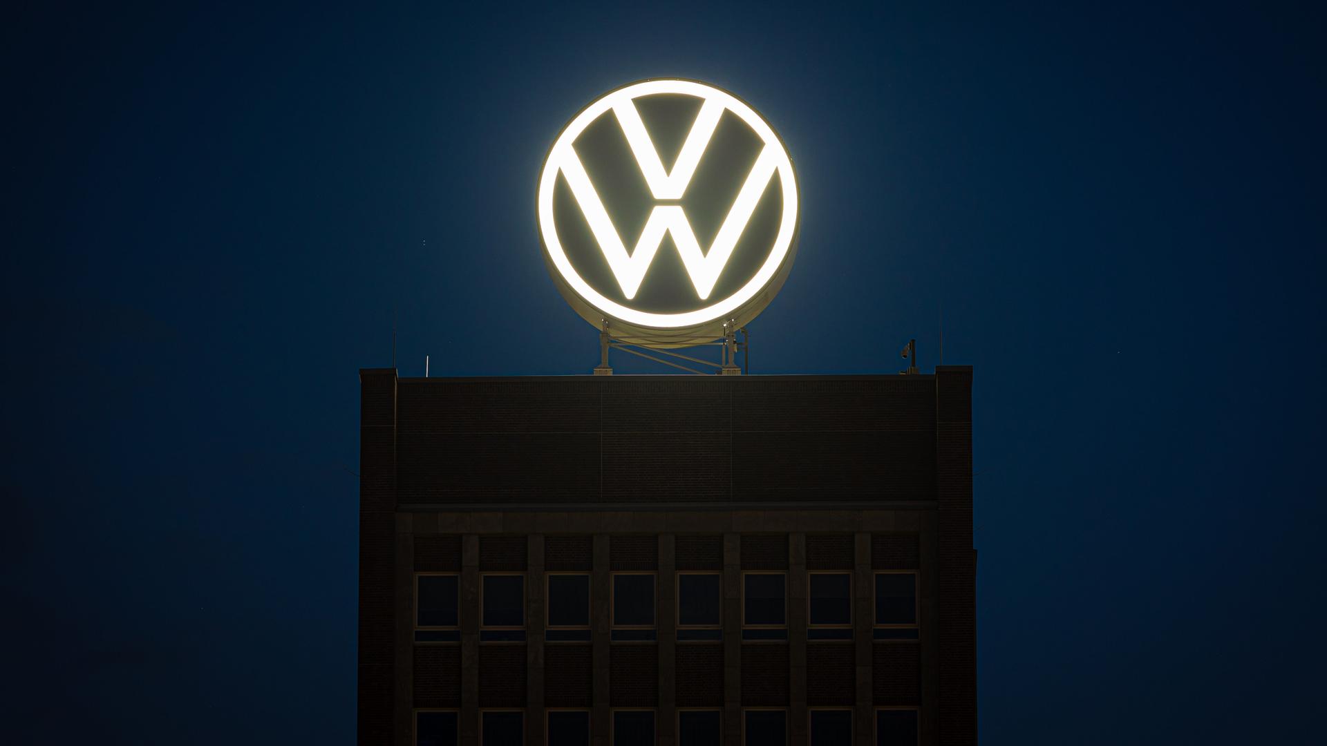 Das VW-Logo leuchtet auf dem Dach des Markenhochhauses im Volkswagen Stammwerk am frühen Morgen. Volkswagen hat angekündigt, wegen der angespannten Lage der Kernmarke den Sparkurs zu verschärfen. 