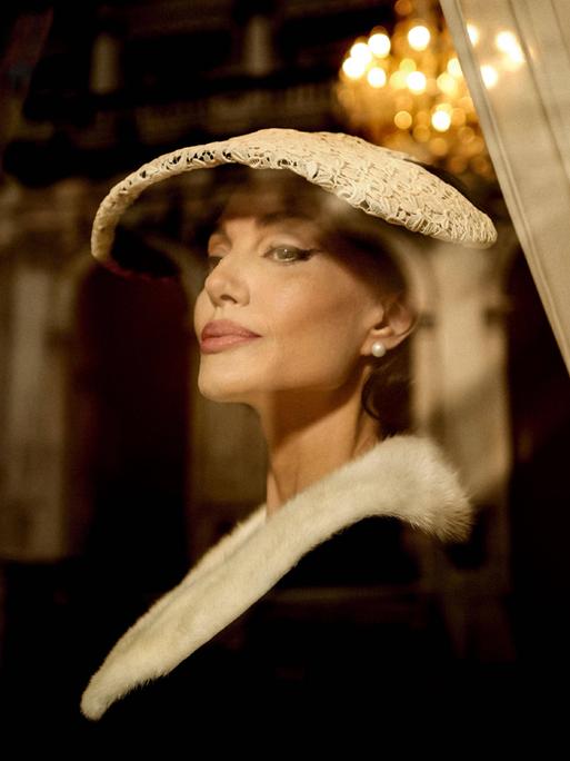 Die US-Schauspielerin Angelina Jolie in der Rolle der Opernsängerin Maria Callas. Sie trägt ein elegantes Kostüm mit Hut im Stil der 1950er-Jahre.
