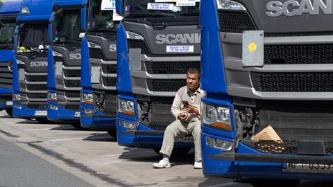Ein Trucker aus Osteuropa sitzt an der Raststätte Gräfenhausen vor dem Kühlergrill seines Lkw. 
