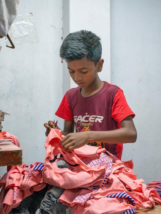 Ein Junge arbeitet bei einem Bekleidungshersteller in Dhaka, Bangladesch.